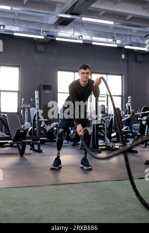 uomo ambizioso e motivato che fa onde con corde, foto a tutta lunghezza. motivazione, lo sportivo si concentra sull'allenamento Foto Stock