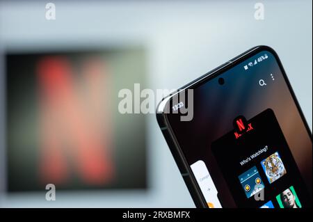 New York, USA - 20 agosto 2023: Utilizzo dell'app mobile del servizio Netflix sullo schermo dello smartphone in primo piano con sfondo sfocato del logo Foto Stock