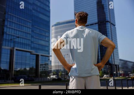 Vista posteriore di una persona irriconoscibile in abiti casual sullo sfondo di grattacieli Foto Stock