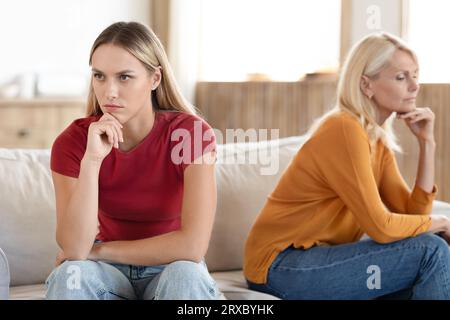 Donne arrabbiate figlia adulta millenaria e madre matura si siedono da parte Foto Stock