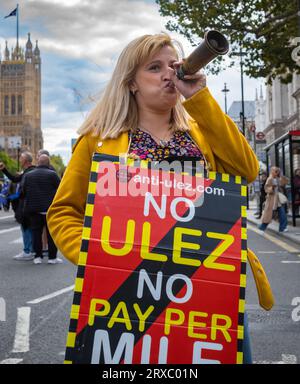 Londra / Regno Unito - 23 settembre 2023: Una donna porta un cartello anti-ULEZ (Ultra Low Emission zone) e fa saltare un corno a una protesta a Whitehall, Westminster, in C. Foto Stock