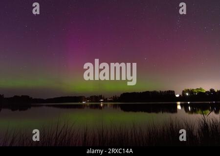 Immagine notturna di un'imponente e vibrante aurora boreale verde multicolore, Aurora Polaris conosciuta anche come l'aurora boreale nel cielo notturno sopra un lago, L. Foto Stock