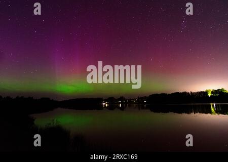 Immagine notturna di un'imponente e vibrante aurora boreale verde multicolore, Aurora Polaris conosciuta anche come l'aurora boreale nel cielo notturno sopra un lago, L. Foto Stock