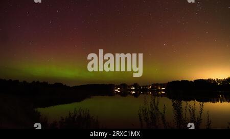 Immagine notturna di un'imponente e vibrante aurora boreale verde multicolore, Aurora Polaris conosciuta anche come l'aurora boreale nel cielo notturno sopra un lago, L. Foto Stock
