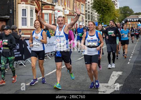 Warrington, Cheshire, Regno Unito. Domenica 24 settembre 2023 - Warrington, Cheshire, Inghilterra, Regno Unito - si è svolto il primo festival al mondo di corsa su strade chiuse e chiuse. 6000 corridori lasciarono Bank Park e Warrington Town Hall per iniziare la loro gara. Alcuni erano felici di salutare la telecamera. Crediti: John Hopkins/Alamy Live News Foto Stock