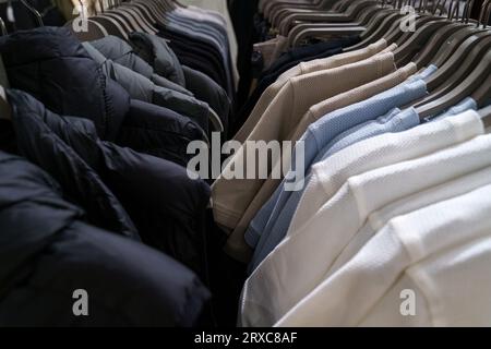 Giacche e T-shirt senza maniche appese ai ganci di un negozio di abbigliamento. Primo piano, sfondo. Foto Stock