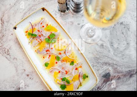 Ceviche di spigola con salsa di arancio e mango su un tavolo di marmo in un ristorante Foto Stock