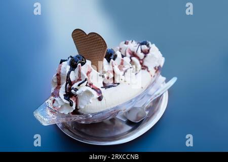 gelato alla banana split in un piatto, isolato su sfondo blu Foto Stock