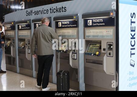 Persone che utilizzano distributori automatici di biglietti presso la stazione ferroviaria di Waterloo a Londra Foto Stock