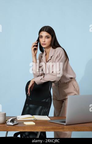 bella donna d'affari in camicia beige che usa il telefono cellulare Foto Stock