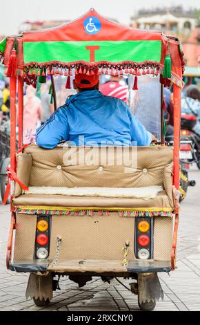 Marrakech, Marocco, 8 aprile 2023. Vista posteriore di un tok tok marocchino con un autista maschio seduto di fronte ad aspettare i clienti a Marrakech Jemaa Foto Stock