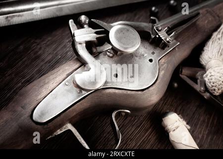 antico muschio di flintlock del xvii secolo con fiasca di polvere e pallottole a led su ponte di legno. Foto Stock
