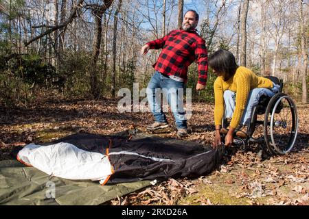 Un paio prepara una tenda in un campeggio. Entrambi sono disabili ma amano l'aria aperta. Foto Stock