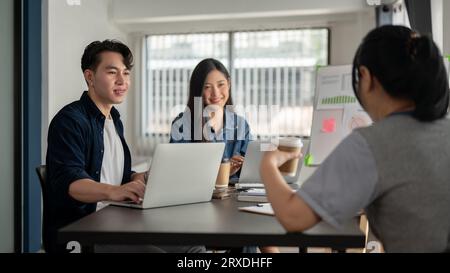 Un gruppo di imprenditori di startup asiatiche sta discutendo insieme un nuovo progetto nella sala riunioni. Lavoro di squadra, collaborazione, colleghi Foto Stock