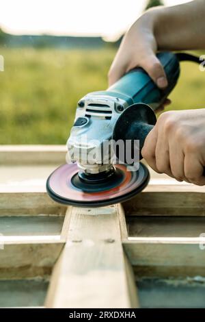 Levigatura del legno, restauro e restauro di mobili. Un falegname sabbia una vecchia finestra nella sua officina. Foto di alta qualità Foto Stock