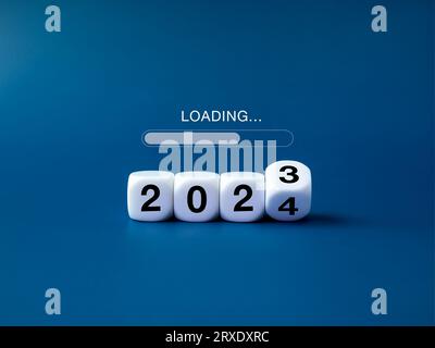 Caricamento per buon natale e inizio di un felice anno nuovo 2024 sfondo banner. Caricamento, il testo viene visualizzato su blocchi di capovolgimento bianchi con la modifica 2023 in 2024 Foto Stock