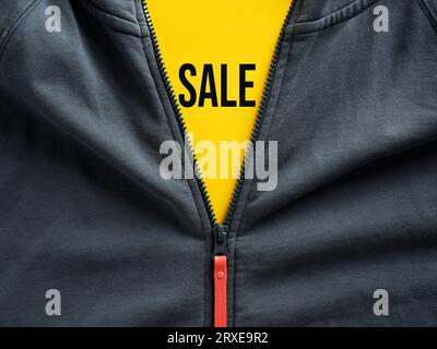 Cerniera aperta di una felpa con cappuccio che mostra l'offerta di vendita sul cartellino giallo. Sconto sugli outlet di moda e promozione sui prezzi di abbigliamento. Foto Stock