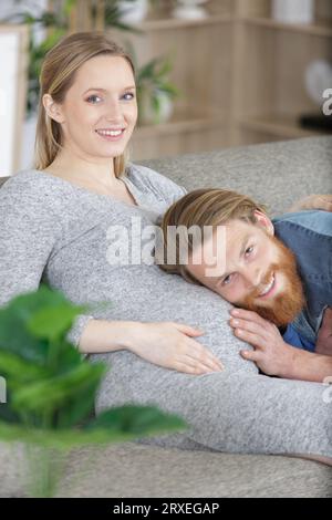 l'uomo ascolta la pancia di sua moglie Foto Stock