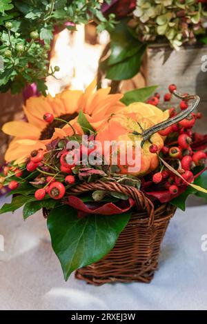 Bouquet autunnale di splendidi fiori, frutti di bosco e zucca nel cestino presso il fioraio all'aperto. Concetto di decorazione autunnale per il Ringraziamento Foto Stock