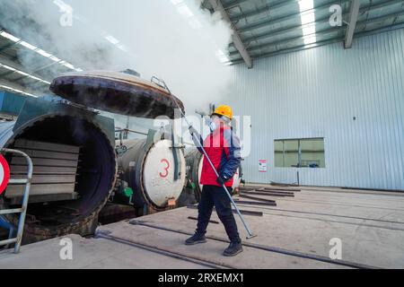 Luannan, Cina - 13 febbraio 2023: I lavoratori controllano le attrezzature di trazione per il trasporto di nuovi materiali da costruzione - pannelli silicati di calcio - da autoclavi Foto Stock