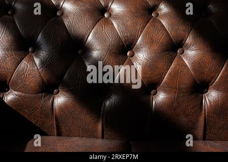 Dettaglio della lussuosa tappezzeria del divano in pelle marrone trapuntata con bottoni. Design di mobili. Pelle naturale con cuciture rombiche. Arredamento elegante e classico Foto Stock