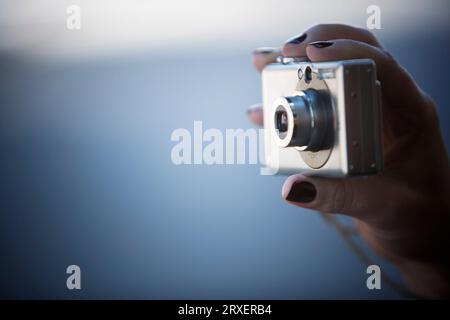 Una mano femminile che regge una fotocamera digitale. Foto Stock