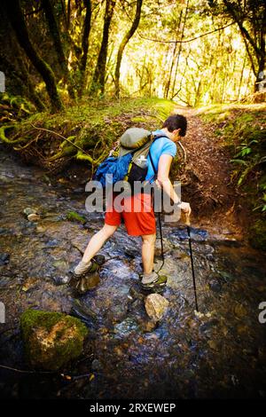 Un'escursionista donna che attraversa un torrente. Foto Stock
