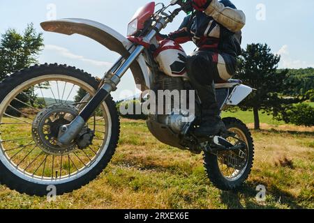 Un pilota professionista di motocross impavido esegue con abilità un'estrema manovrabilità all'indietro attraverso un pericoloso terreno forestale, mostrando una straordinaria esperienza Foto Stock