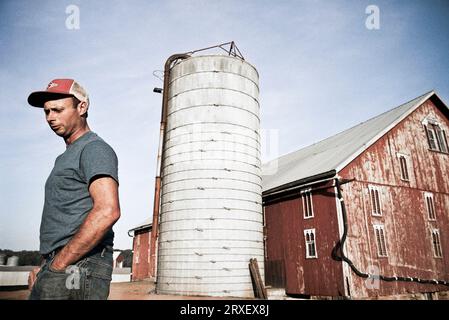 Un uomo si trova di fronte al fienile e al silo della fattoria di famiglia a Keymar, Maryland. Foto Stock