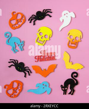 Ritagli colorati in legno dei simboli di halloween scattati dall'alto su sfondo rosa. Foto Stock