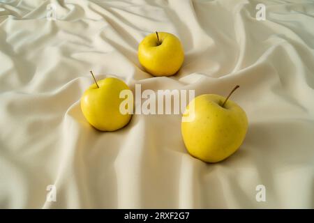 Mele gialle biologiche su lussuosa seta sabbiosa. Idea di cibo sano. Concetto creativo minimale di semplicità. Foto Stock
