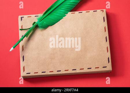Una penna a forma di penna quill e una pila di buste vuote su sfondo rosso, modello per la progettazione Foto Stock
