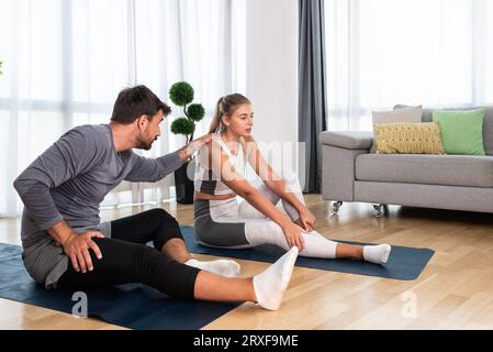 Coppia che si allenano insieme. Uomo e donna in abbigliamento sportivo che si allenano a casa. I partner che fanno lezioni di yoga nell'appartamento su materassini yoga che allungano musc Foto Stock