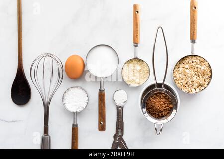 Una fila di utensili da forno e ingredienti su marmo bianco. Foto Stock