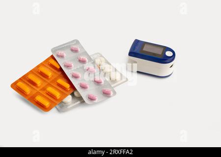Misuratore di impulsi cardiaci portatile per dito e blister per pillole mediche su sfondo bianco con spazio per la copia Foto Stock