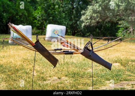 Due archi di legno con frecce sullo sfondo dei bersagli. Una gara di tiro con l'arco. Arma per sparare frecce. Coppia tiro con l'arco Foto Stock