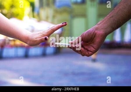 L'uomo suggerisce alla donna di fumare! Il problema sociale. l'uomo offre una sigaretta alla donna. Smettere di fumare. Per smettere di fumare. Foto Stock