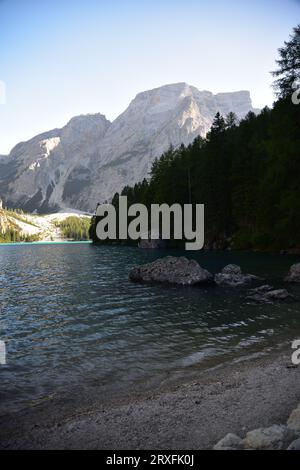 Piccola spiaggia sul Lago di Braies alla luce della fine della giornata con il massiccio della Croda del becco ancora illuminato dai raggi del sole Foto Stock