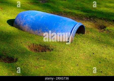 Una grande botte di plastica blu sepolta nel terreno. Un posto dove si possono nascondere piccoli animali domestici. Foto Stock
