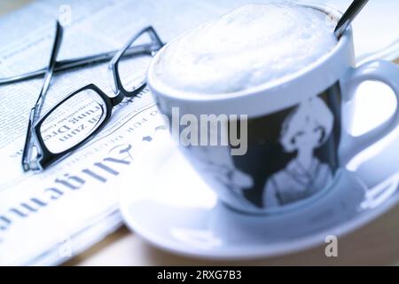 Tazza di cappuccino, giornale e bicchieri Foto Stock