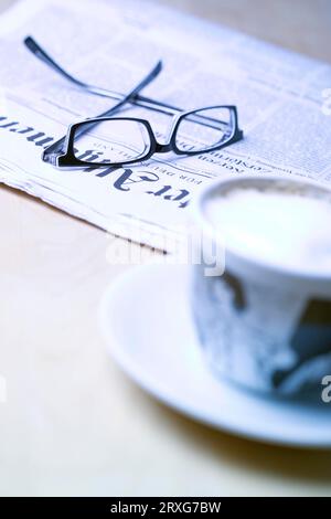 Tazza di cappuccino, giornale e bicchieri Foto Stock