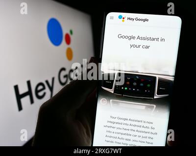 Persona che tiene il cellulare con pagina Web del software di assistenza virtuale Google Assistant sullo schermo con logo. Concentrarsi sul centro del display del telefono. Foto Stock