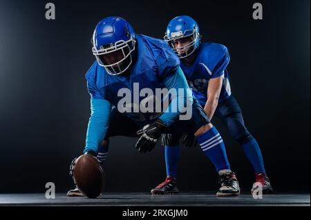 Due giocatori di calcio americani sono pronti per iniziare la partita su uno sfondo nero. Foto Stock