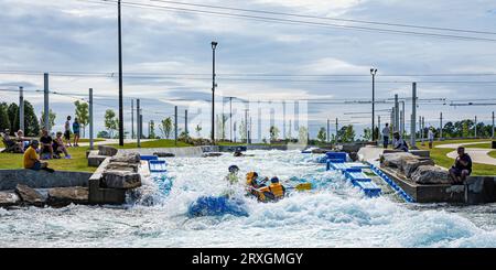 Montgomery, Alabama, USA, settembre 2, 2023: Rafting sul fiume artificiale al parco di Montgomery Whitewater e al complesso di acque bianche. Molte persone si siedono lungo la c Foto Stock