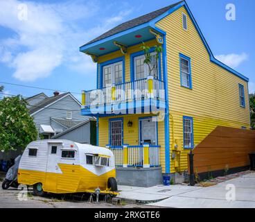 NEW ORLEANS, LOUISIANA, USA - 23 LUGLIO 2023: Colorata dimora storica con un colorato rimorchio in miniatura parcheggiato di fronte nel quartiere di Marigny Foto Stock