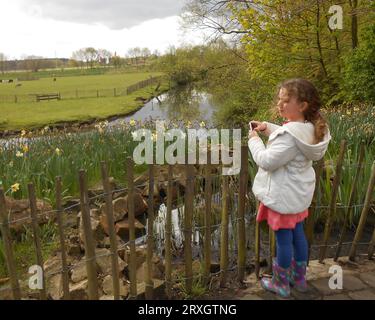 Una bambina di 6 anni si affaccia sul fiume Vecht vicino a Nordhorn, in Germania. Ha capelli biondi ricci e stivali colorati Foto Stock