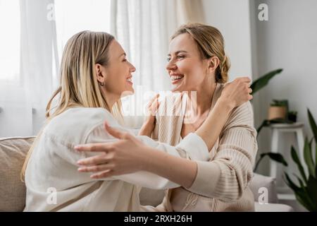 bellissime sorelle in un abbigliamento alla moda sorridenti che si guardano e si abbracciano, legano con la famiglia Foto Stock