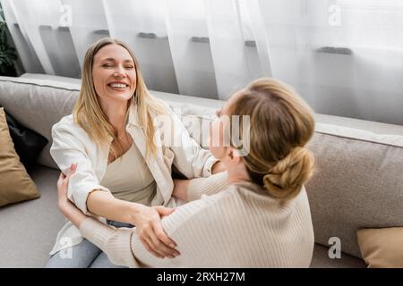 adorabili sorelle in abiti alla moda che ridono e si guardano l'un l'altra, mano su spalla, incollaggio Foto Stock