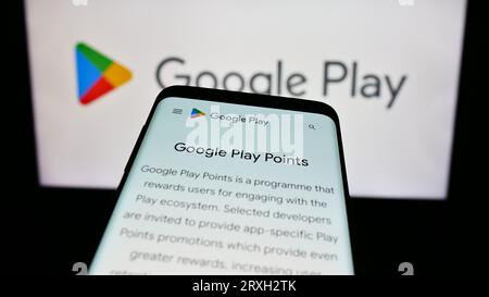 Telefono cellulare con pagina Web della piattaforma di distribuzione delle app Google Play sullo schermo davanti al logo aziendale. Mettere a fuoco in alto a sinistra sul display del telefono. Foto Stock