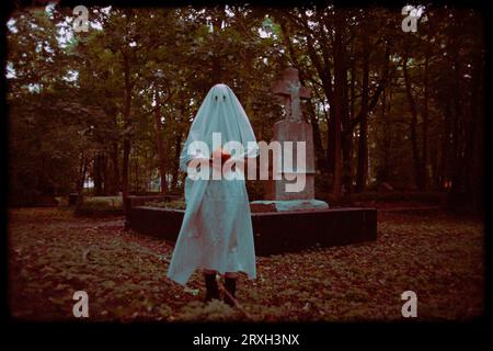 L'inquietante fotografia cattura una figura fantasma che tiene in mano la zucca di un martinetto mentre si trova in un cimitero al crepuscolo. Halloween, misticismo e orrore. La d Foto Stock